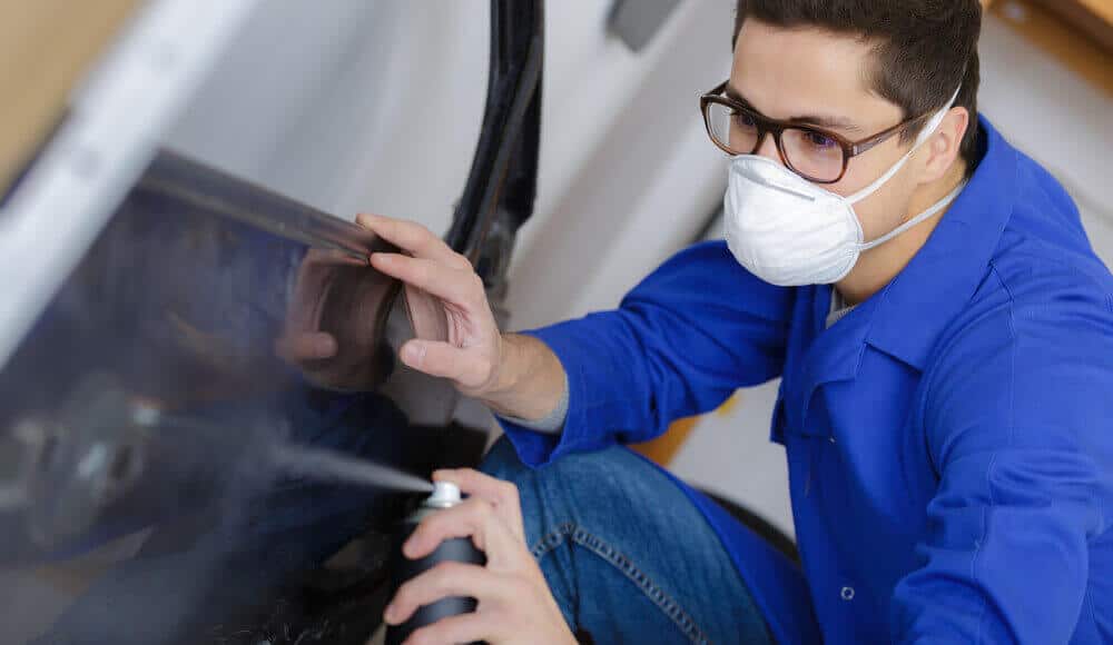 Paint technician is spray a clear coat on the car body.