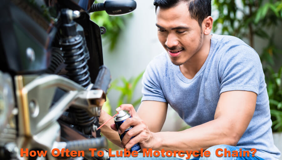 Man oiling and spraying motorcycle chain lube.