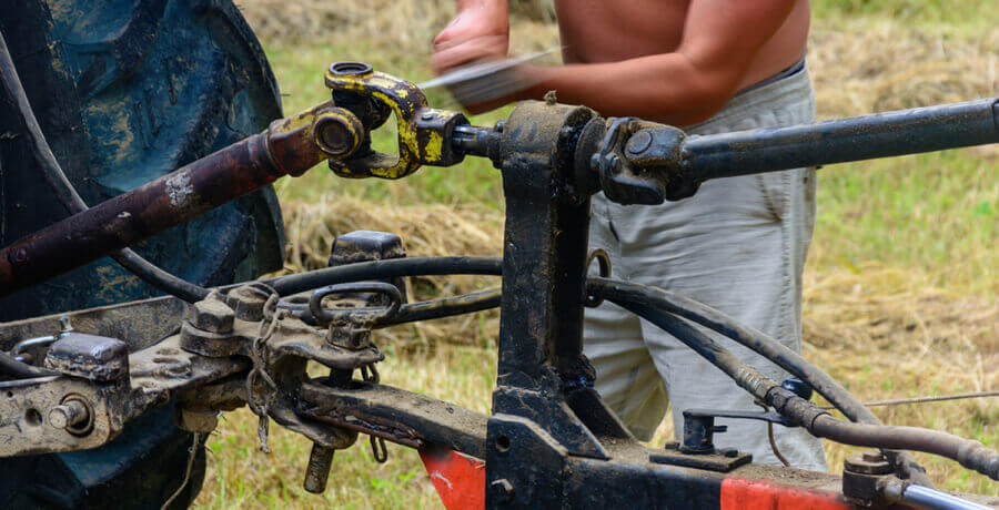 Mechanic connecting the tractor PTO shaft to the implement.