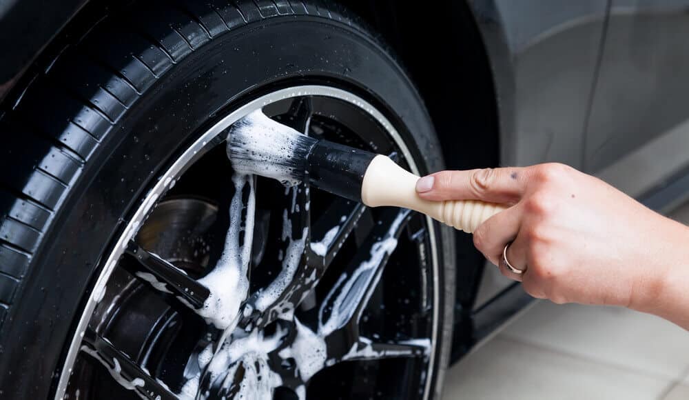 Car owner is cleaning up the tire from the brake dust.